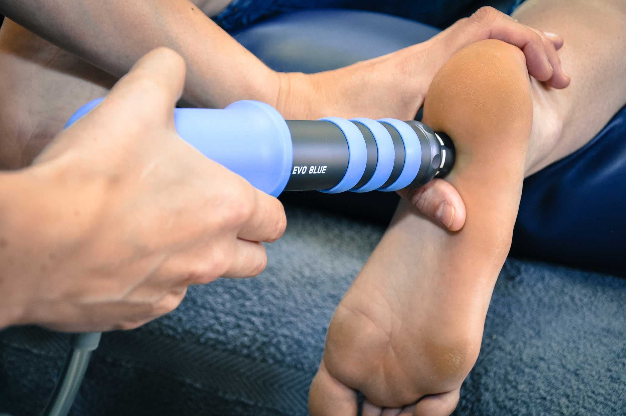 Square One - Shockwave Therapy: Image showing practitioner using shockwave therapy on foot of a patient